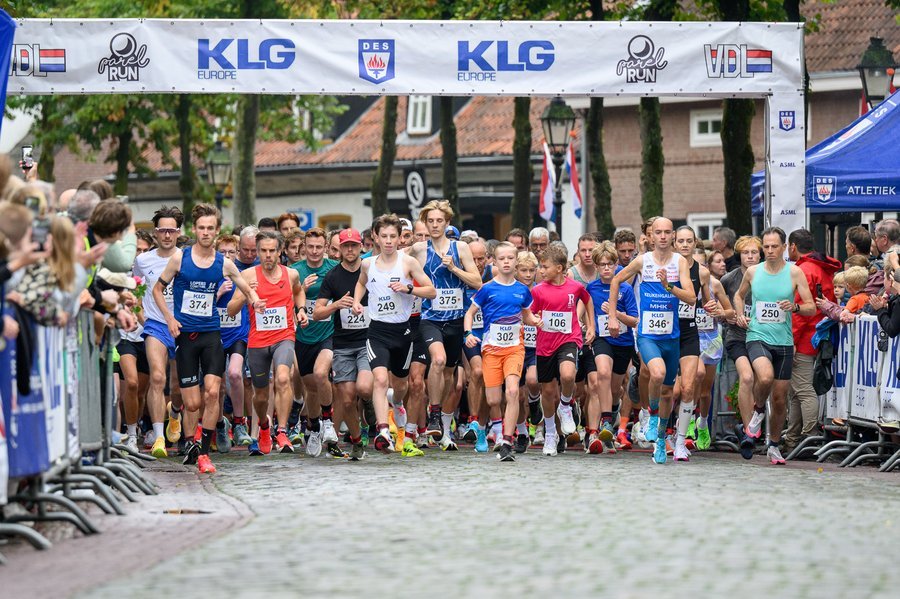 Massastart van de Parelrun, met de startboog en sponsors op de achtergrond