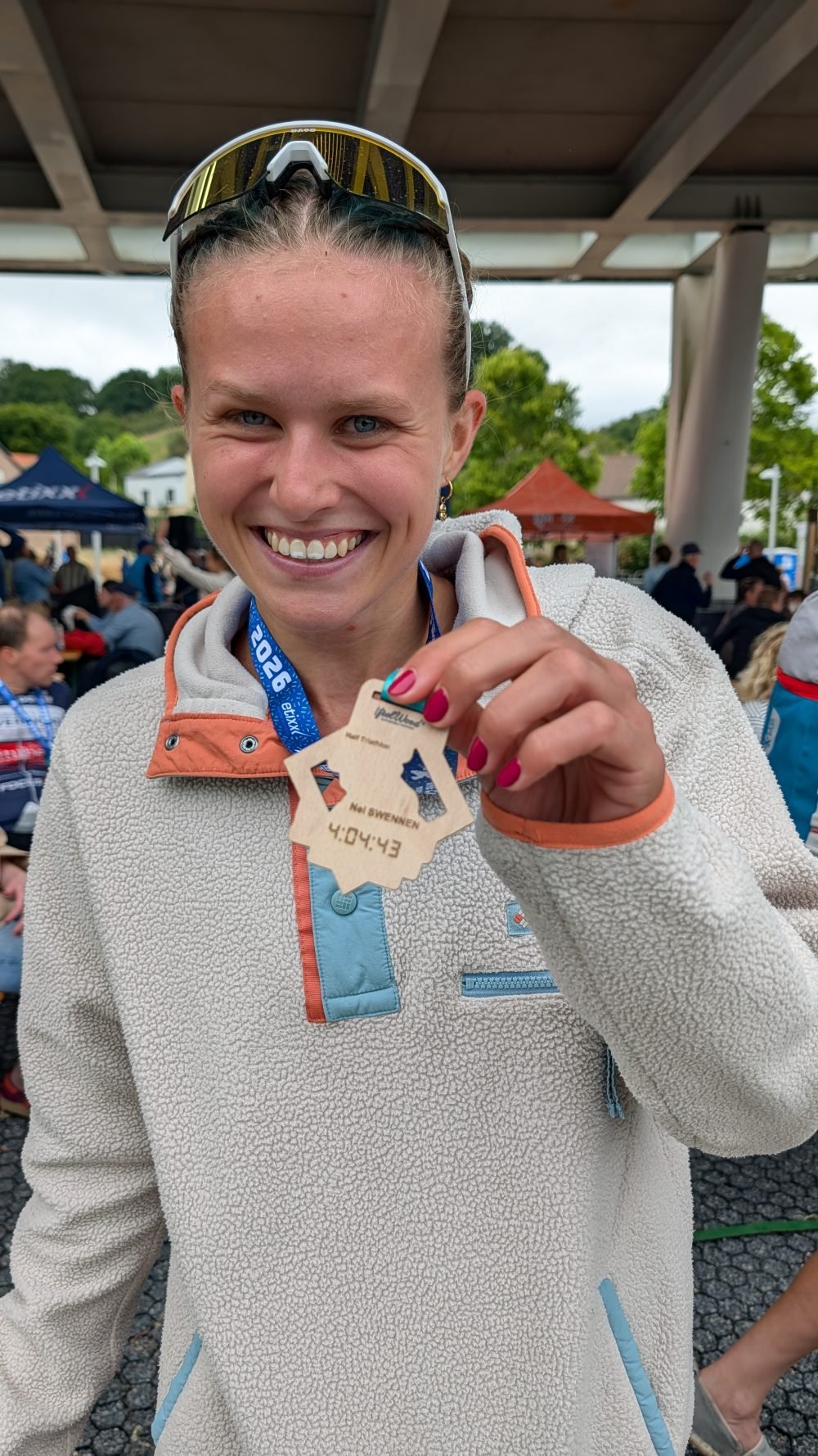 Lachende deelneemster toont haar gepersonaliseerde houten finisher-medaille